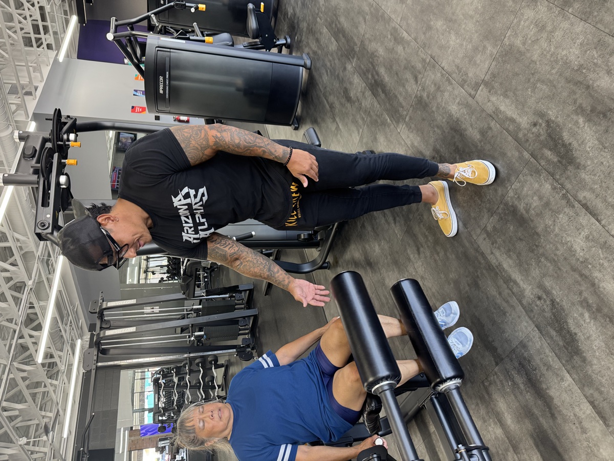 Coach guiding a senior member onto the leg press machine